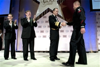 U.S. Navy Adm. Mike Mullen, chairman of the Joint Chiefs of Staff, congratulates U.S Navy Petty Officer 2nd Class William S. Stevens as the USO Sailor of the Year at the 2009 USO Gala at the Marriott Wardman Park, Washington, D.C., Oct. 7, 2009, as USO President and CEO Sloan Gibson, left, and USO Chairman of Board of Governors Edward T. Reilly applaud. DoD photo by U.S. Navy Petty Officer 1st Class Chad J. McNeeley